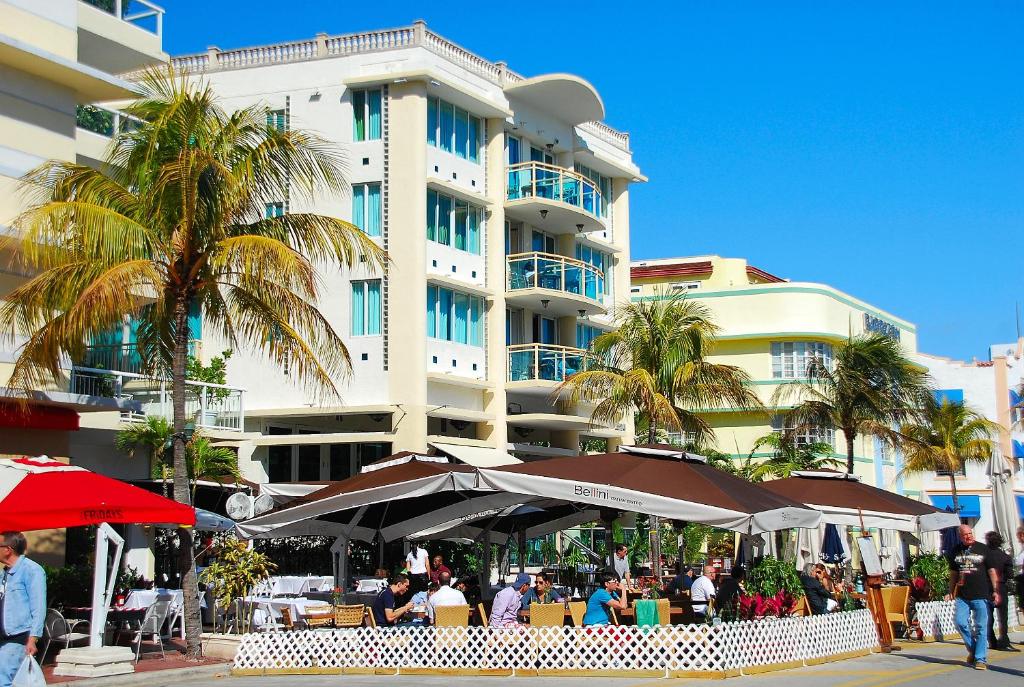 un hotel con mesas y sombrillas frente a un edificio en The Fritz Hotel, en Miami Beach