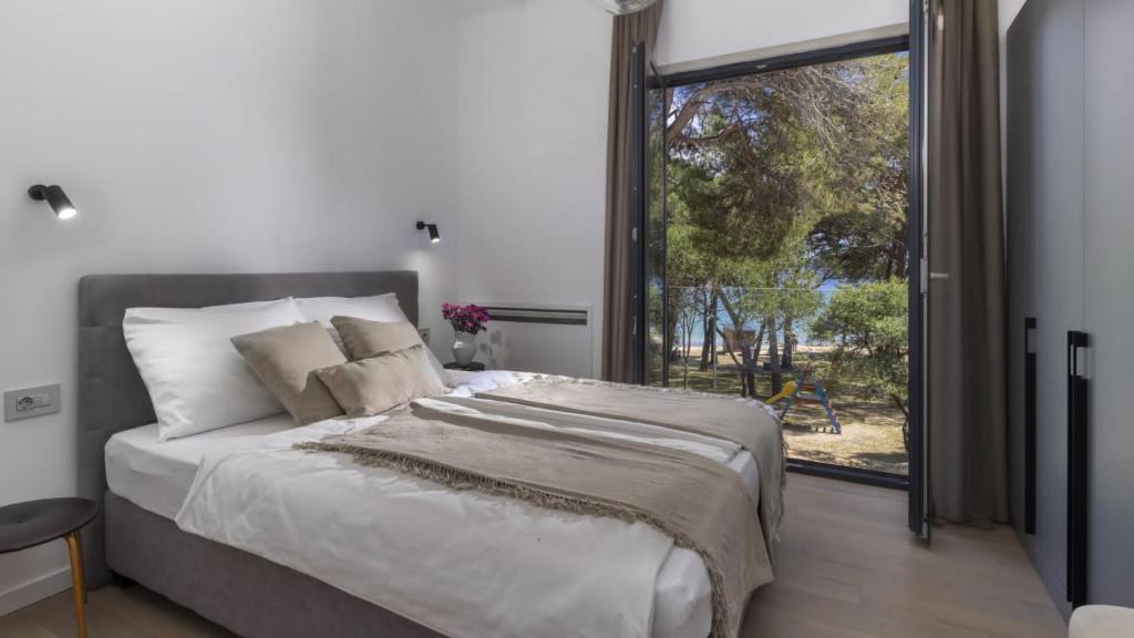 a bedroom with a large bed and a large window at Mare Solis Pinea in Mali Lošinj