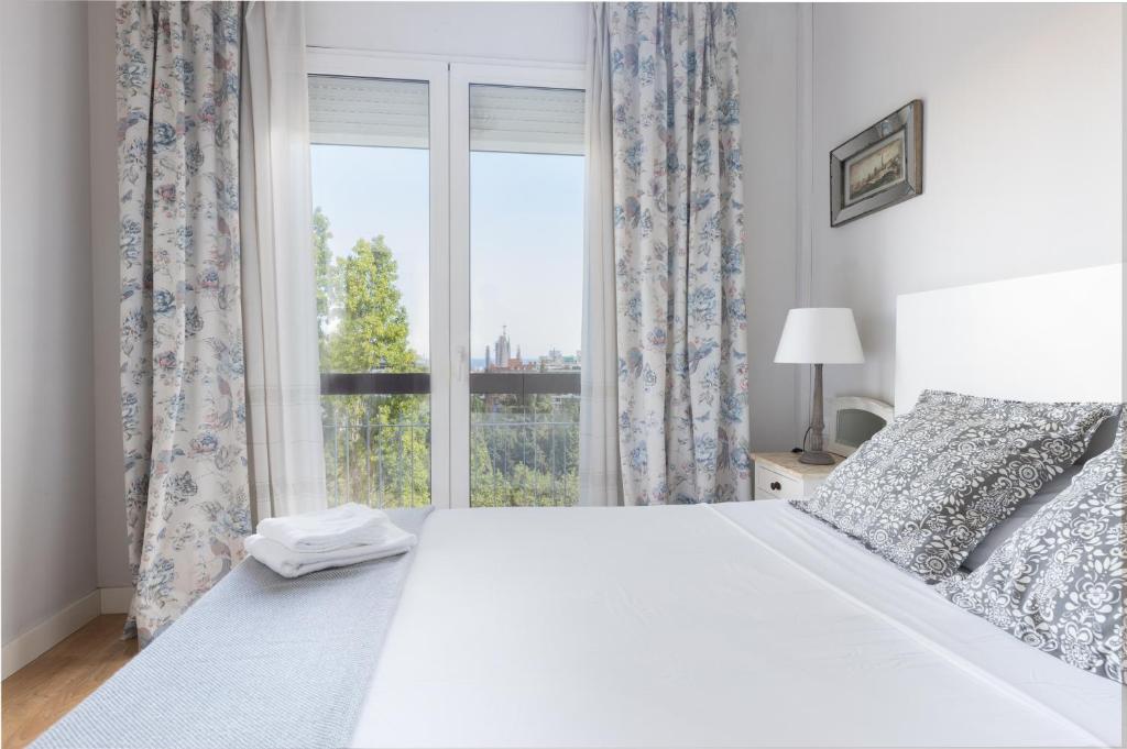 Un dormitorio con una gran cama blanca y una ventana en Lodging Apartments Guell Gaudi, en Barcelona