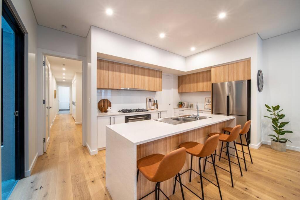 a kitchen with a white counter and chairs in it at SYLO Luxury Apartments - 1Gb Fibre Internet in Adelaide