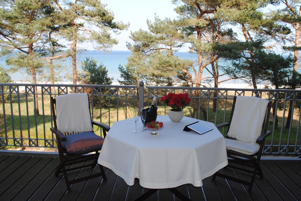 a table and two chairs on a deck with the ocean at Panorama-Meerblick in der Villa Atlantic mit Strandkorb am Strand in Binz