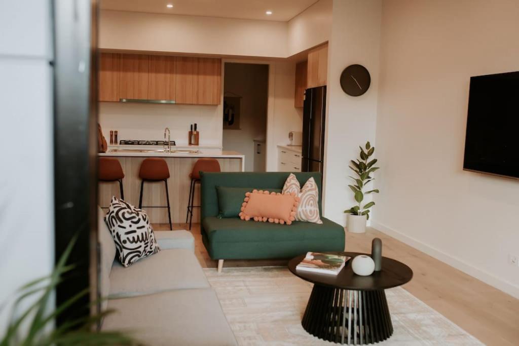 ein Wohnzimmer mit einem grünen Sofa und einem Tisch in der Unterkunft SYLO Luxury Apartments - LVL 2 in Adelaide