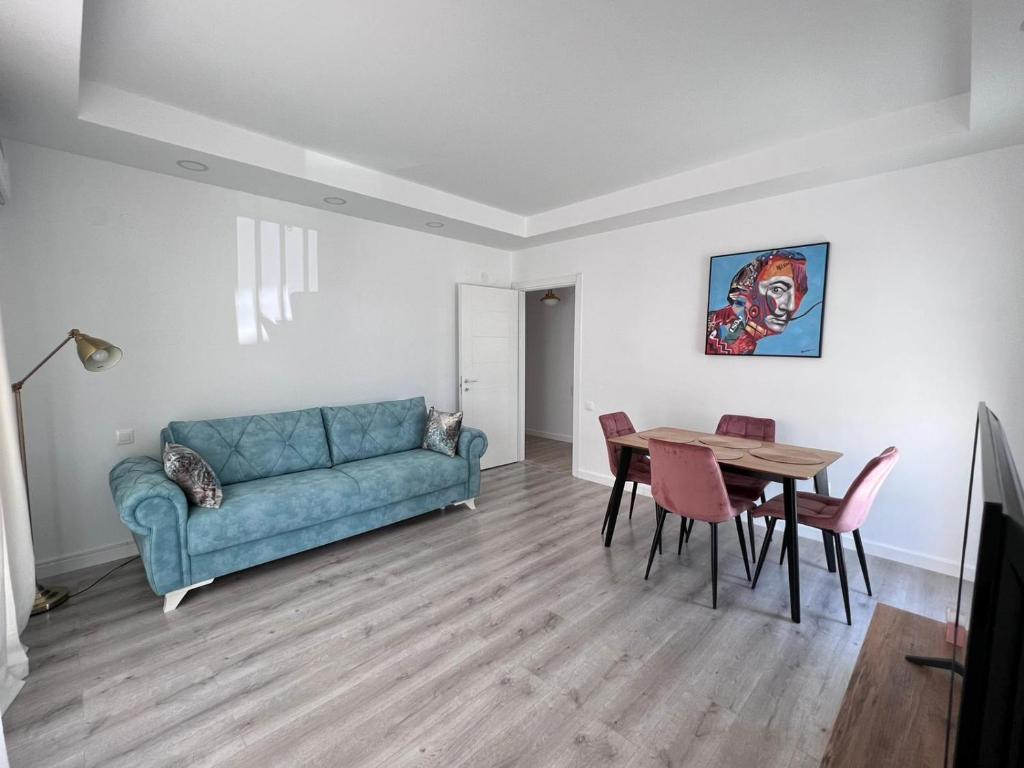 a living room with a blue couch and a table at Cosmopolis Bliss: Your Home Away from Home in Ştefăneştii de Jos