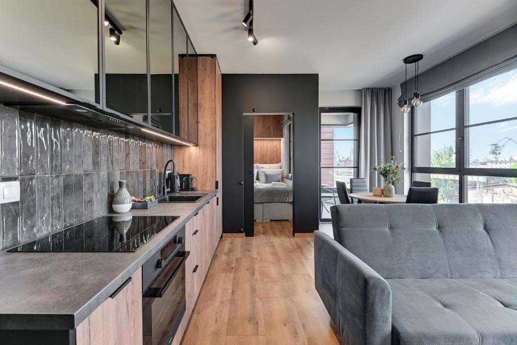 a living room with a couch and a kitchen at Downtown Apartments DOKI Living & Foodhall in Gdańsk