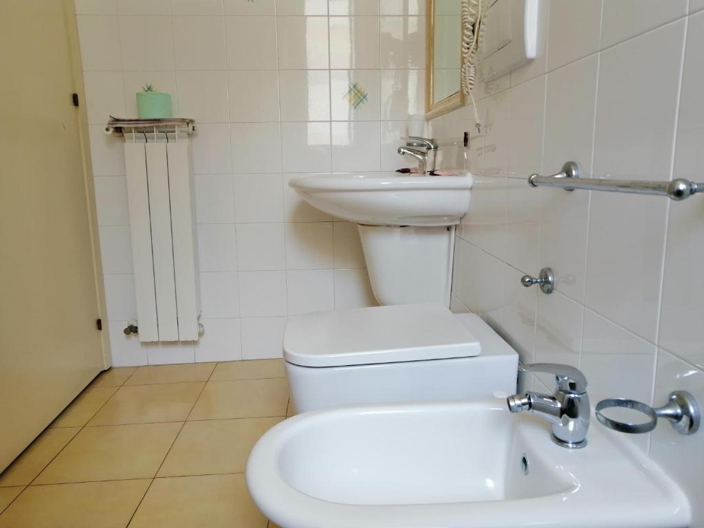 a white bathroom with a toilet and a sink at Megaron Hotel in Pozzallo