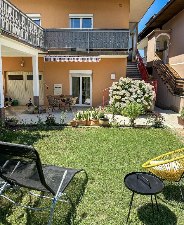 a yard with chairs and tables and a house at Apartments Dent in Umag
