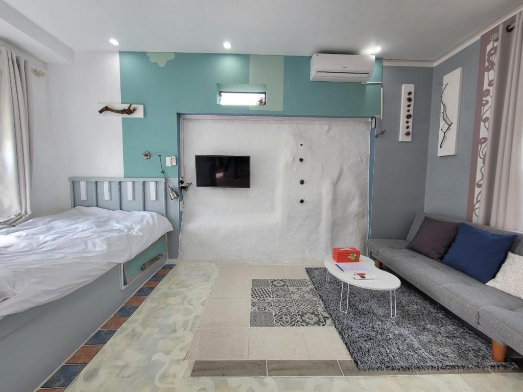 ein kleines Zimmer mit einem Bett und einem Sofa sowie einem Bett und einem Sofa in der Unterkunft Jeju Mermuri in Seogwipo