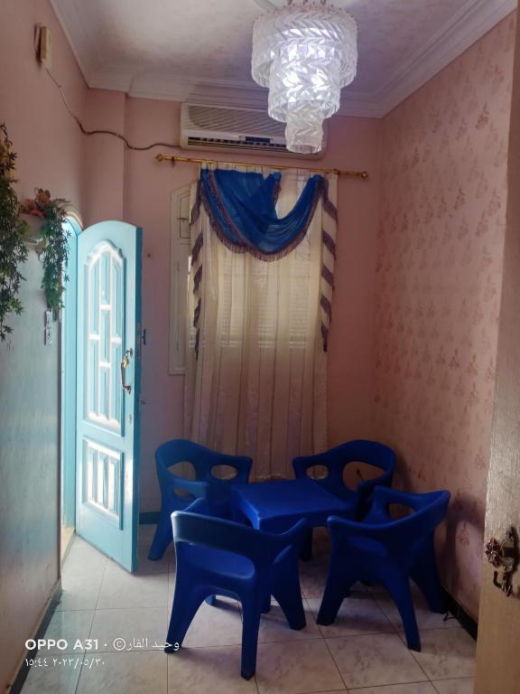 Habitación con mesa azul y sillas junto a una puerta en الوحيد للعقارات, en Ras El Bar