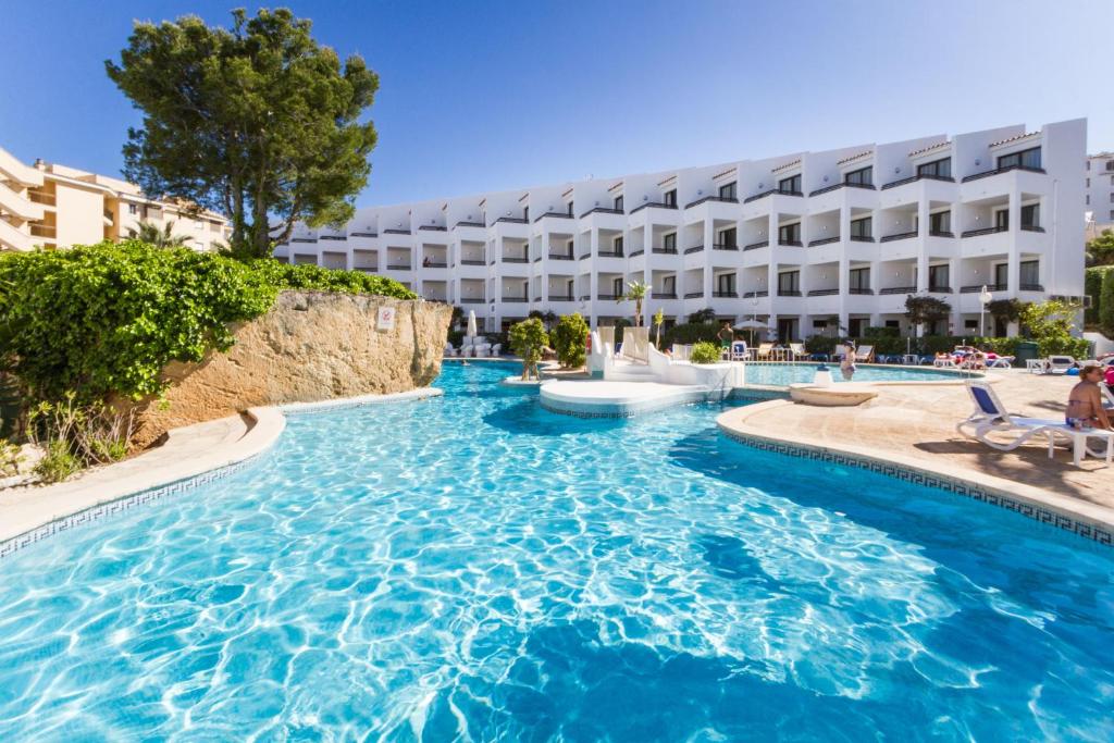 uma piscina com um hotel ao fundo em Plazamar Serenity Resort em Santa Ponsa