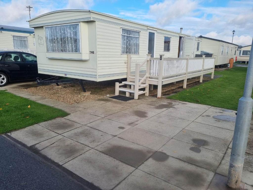 a white mobile home with a porch and a chair at Tm8 6 BERTH 2 BEDROOM CARAVAN P in Chapel Saint Leonards