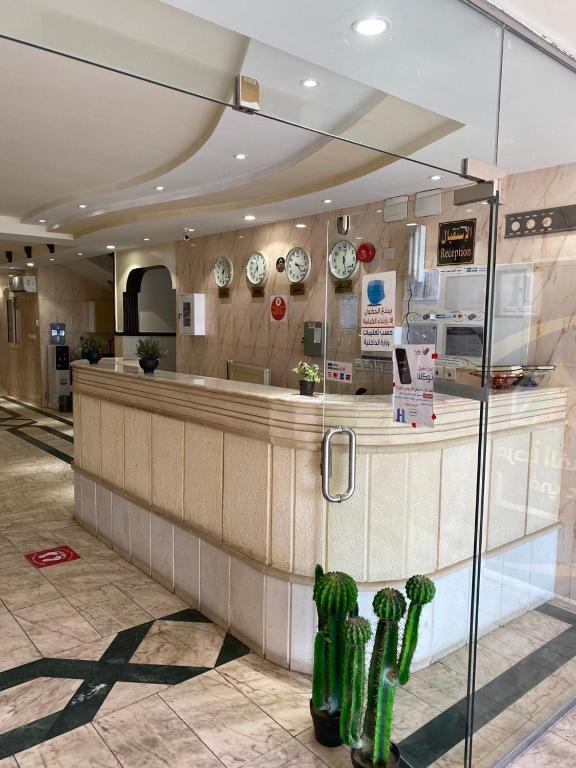 a restaurant with a counter with clocks on the wall at قصر الجادل للشقق المخدومة in Ahad Rafidah