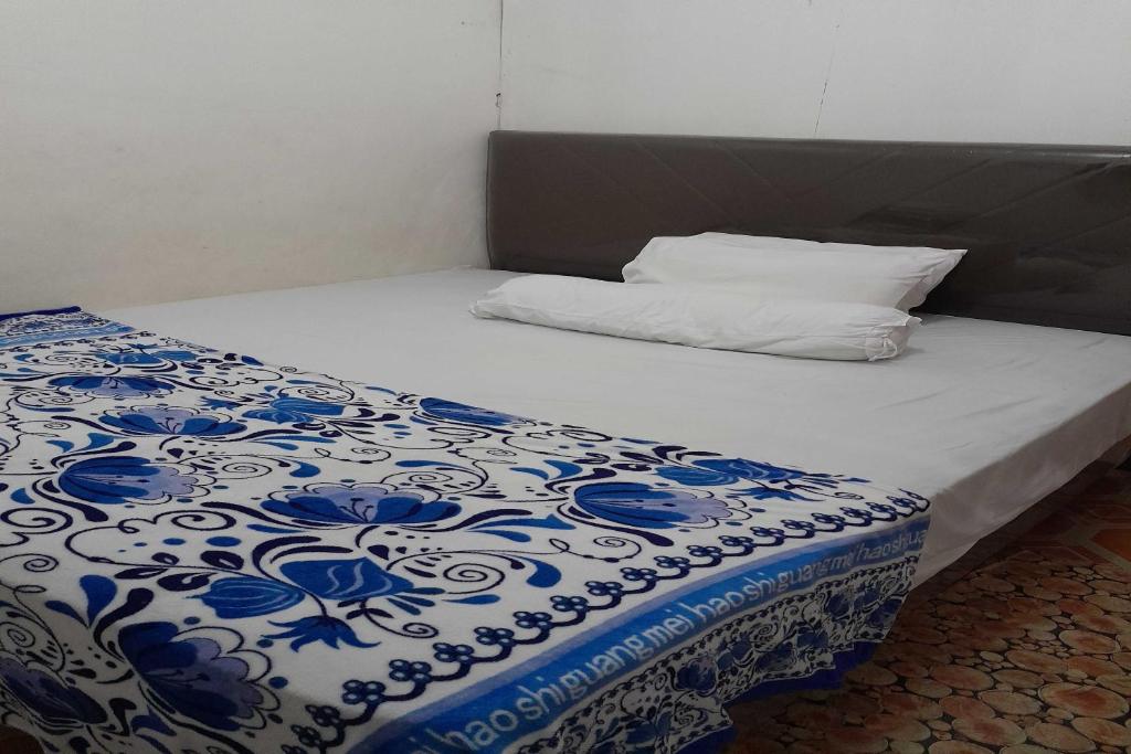 a bed with a blue and white comforter and a pillow at OYO 91477 Fazira Home Stay Syariah in Halangan