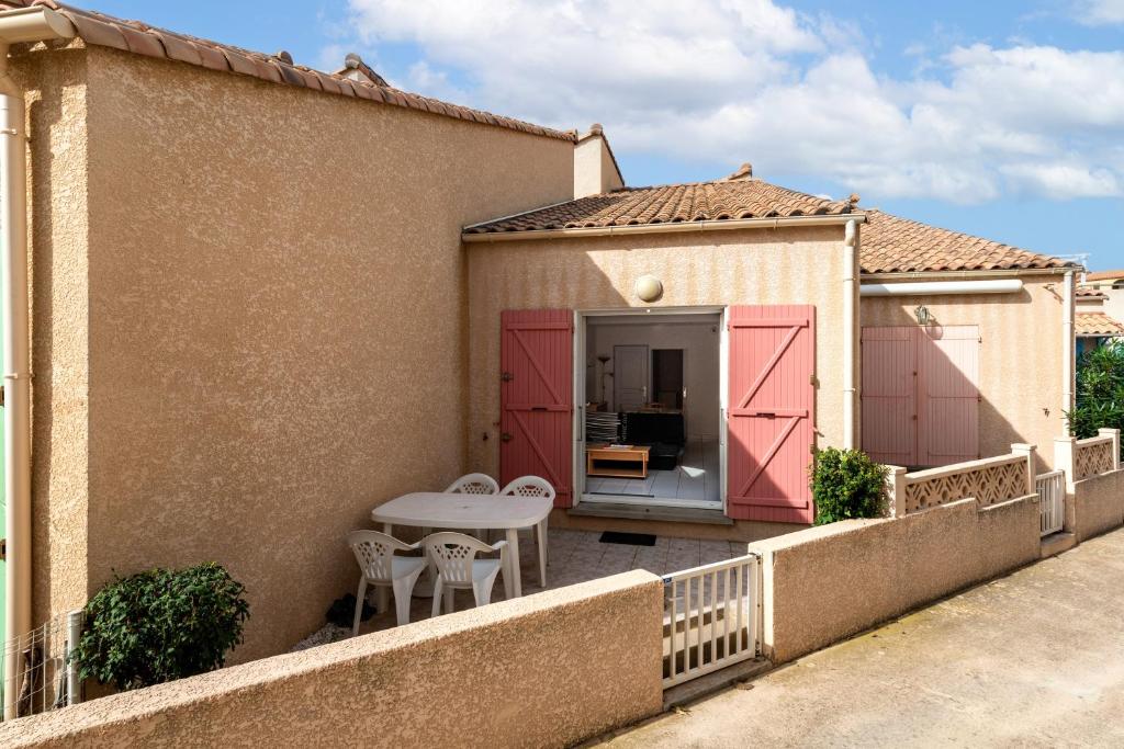 une terrasse avec des portes roses, une table et des chaises dans l'établissement MAISON DE VACANCES Avec PISCINE - MER INDIGO- ST PIERRE LA MER- 700m PLAGE, à Saint Pierre La Mer