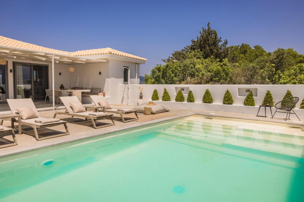 a swimming pool with chairs and a house at Villa Mirto - Iris sunset villas in Lépedha