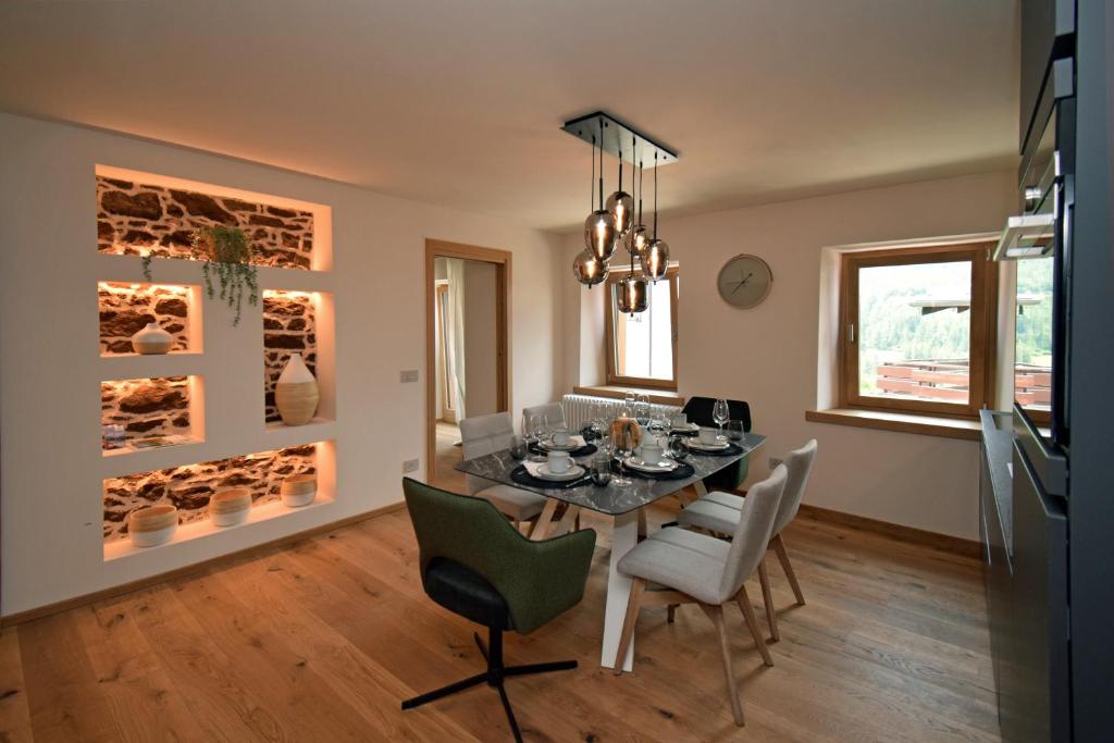 uma sala de jantar com uma mesa com cadeiras e um lustre em Design Residence Nellere em Padola