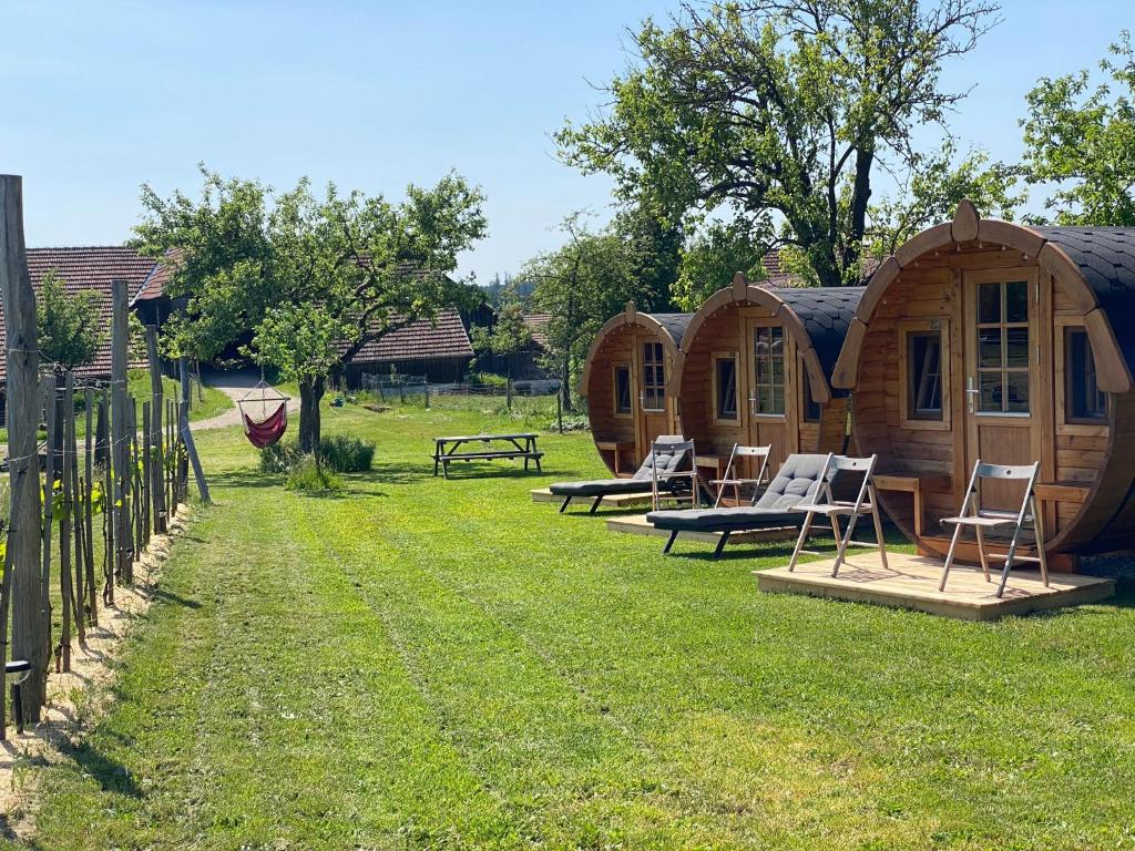 una fila de casas pequeñas en un patio con sillas en Andrella Auszeithof - Schlaferlebnis im Holzfass en Friedersbach