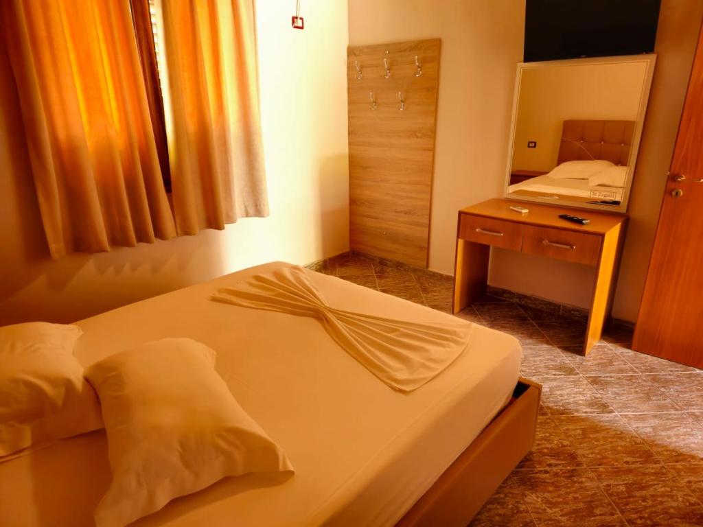 um quarto com uma cama, uma secretária e um espelho em Resort Te Zagolli em Orikum