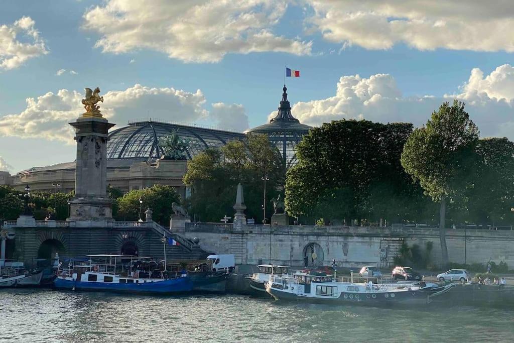 deux bateaux amarrés dans l'eau devant un bâtiment dans l'établissement Péniche de charme au pont Alexandre III, à Paris