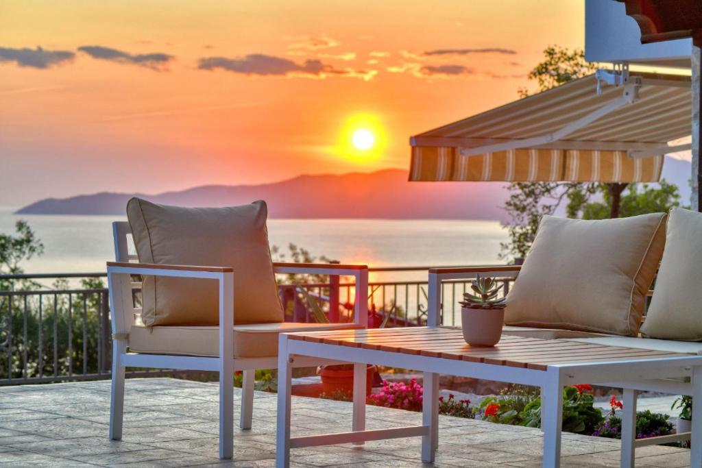 einen Tisch und Stühle auf einem Balkon mit Blick auf den Sonnenuntergang in der Unterkunft Seaview Villa Lavanda with pool in Budva