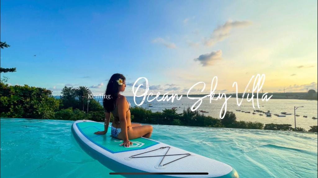 a woman sitting on a surfboard in the water at Sky Villa - 南灣薇拉海景莊園 包棟Villa in Nanwan