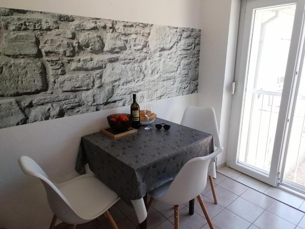 comedor con mesa con sillas blancas y pared de piedra en Studio Punta Pakoštane, en Pakoštane