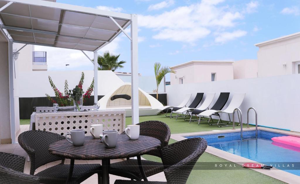 a patio with a table and chairs next to a swimming pool at Royal Dream Villas in Adeje