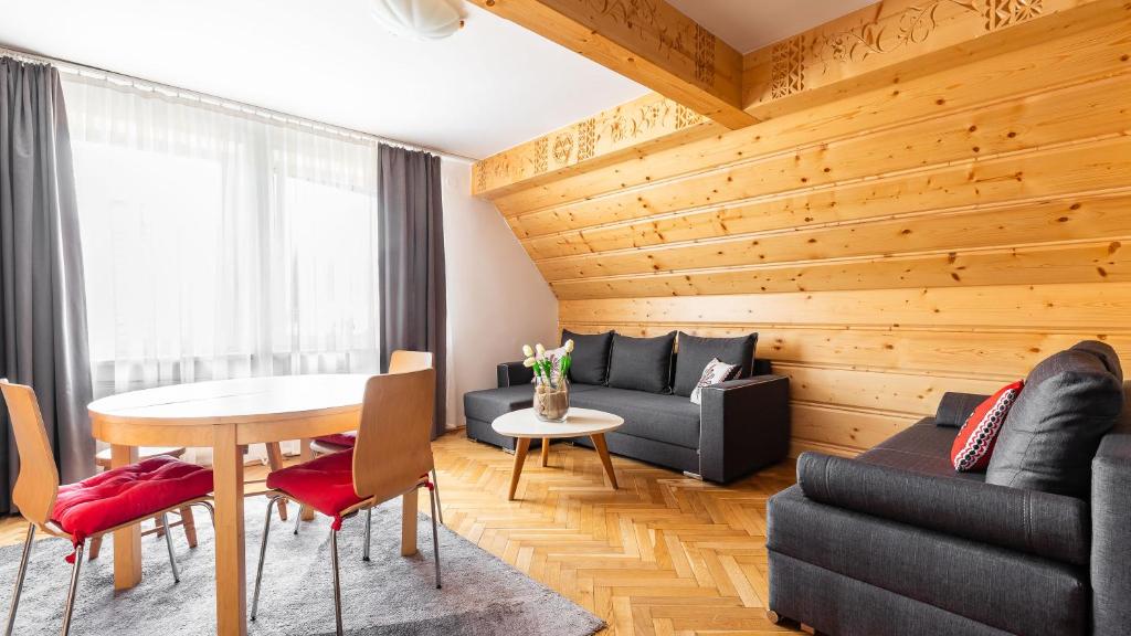 a living room with wooden walls and a table and chairs at Apartament Krzeptowskiego 33 in Zakopane