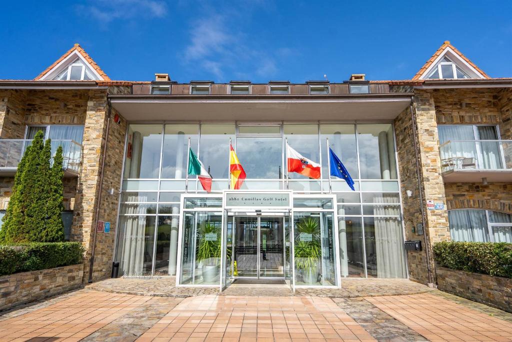 un gruppo di bandiere di fronte a un edificio di Abba Comillas Hotel a Comillas