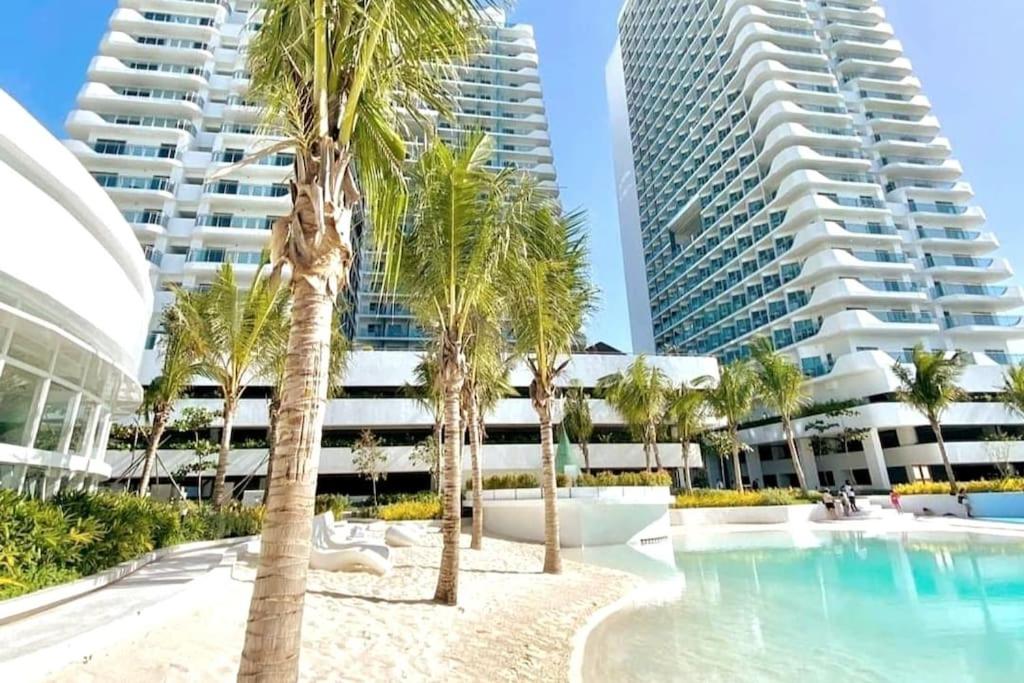 een zwembad met palmbomen voor twee hoge gebouwen bij Pampanga Staycation Condo Unit In San Fernando in San Fernando