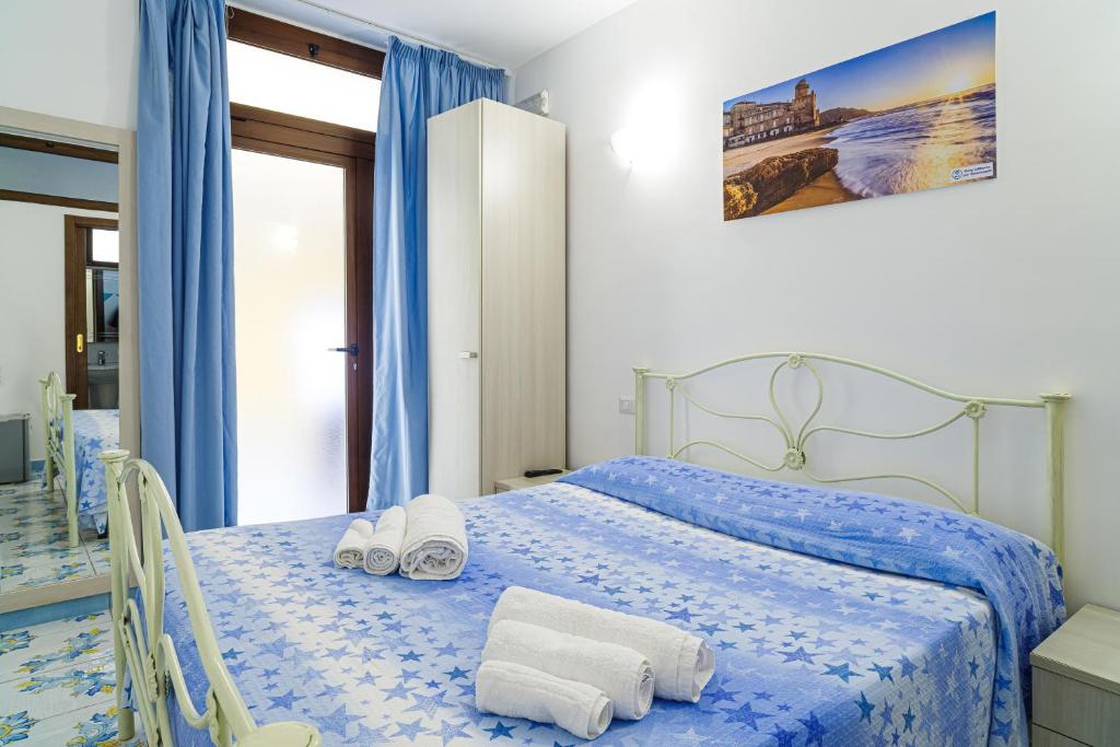 sypialnia z niebieskim łóżkiem i ręcznikami na nim w obiekcie Hotel La Marina w mieście Santa Maria di Castellabate