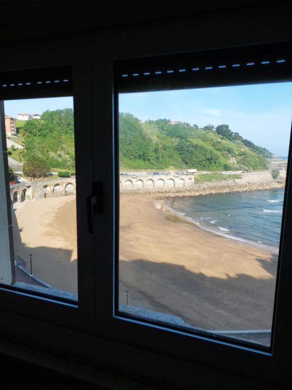 een raam met uitzicht op het strand bij Haitze in Getaria