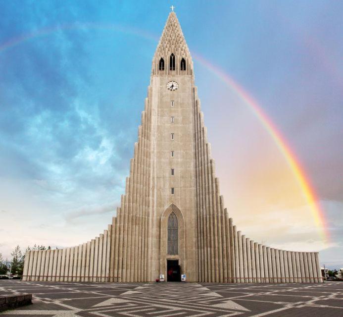 un arcobaleno di fronte a un edificio con una torre dell'orologio di Fox Hotel a Reykjavik