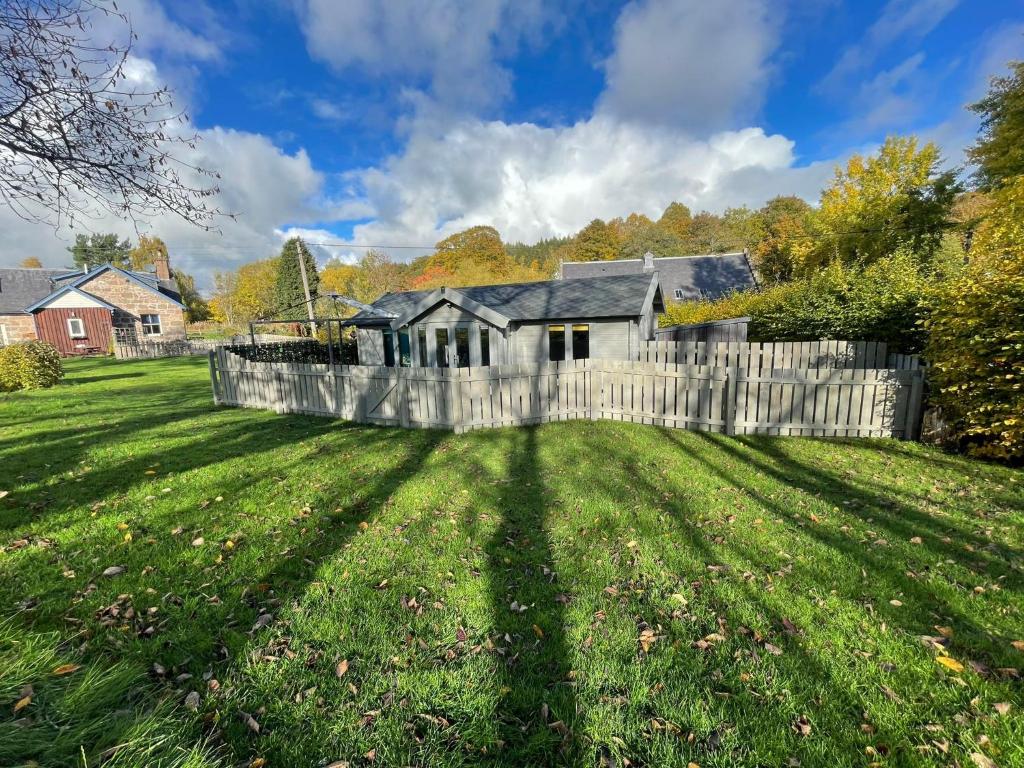 a large yard with a fence and a house at Daisy Cabin in Kincardine OʼNeil