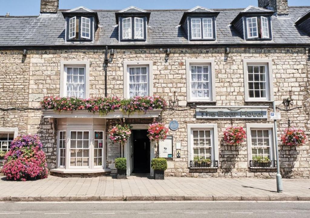 un viejo edificio de piedra con flores delante en The Bear, Cowbridge, en Cowbridge