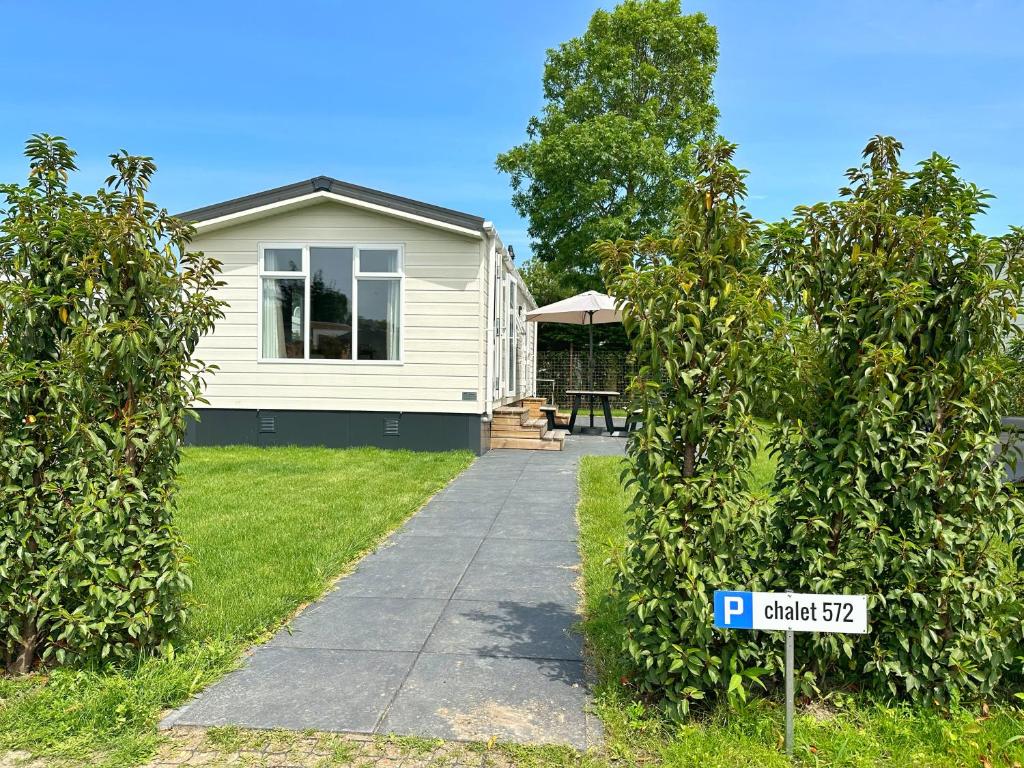 ein weißes Haus mit einem Schild davor in der Unterkunft Chalet 572 op Recreatiepark De Wielen in Sint Maarten