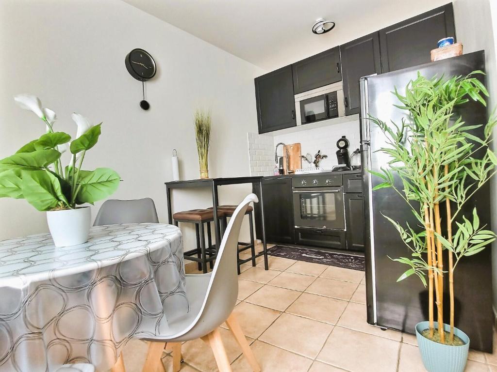 una cocina con armarios negros y una mesa con plantas en Le 3plex - Coeur de Vertou - Original, en Vertou