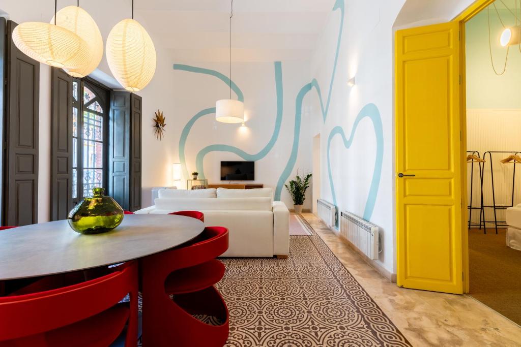 Hotel Apartamento Trahzo, a living room with a table and red chairs at Apartamento Trahzo in Seville