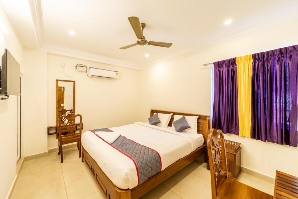a bedroom with a bed and a window with purple curtains at Yellow Residency in Puducherry