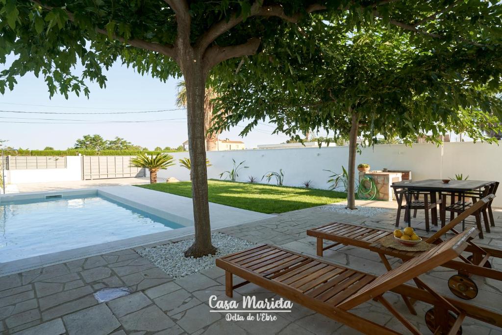 una mesa y un banco junto a una piscina en La Casa de Marieta "A", en Deltebre