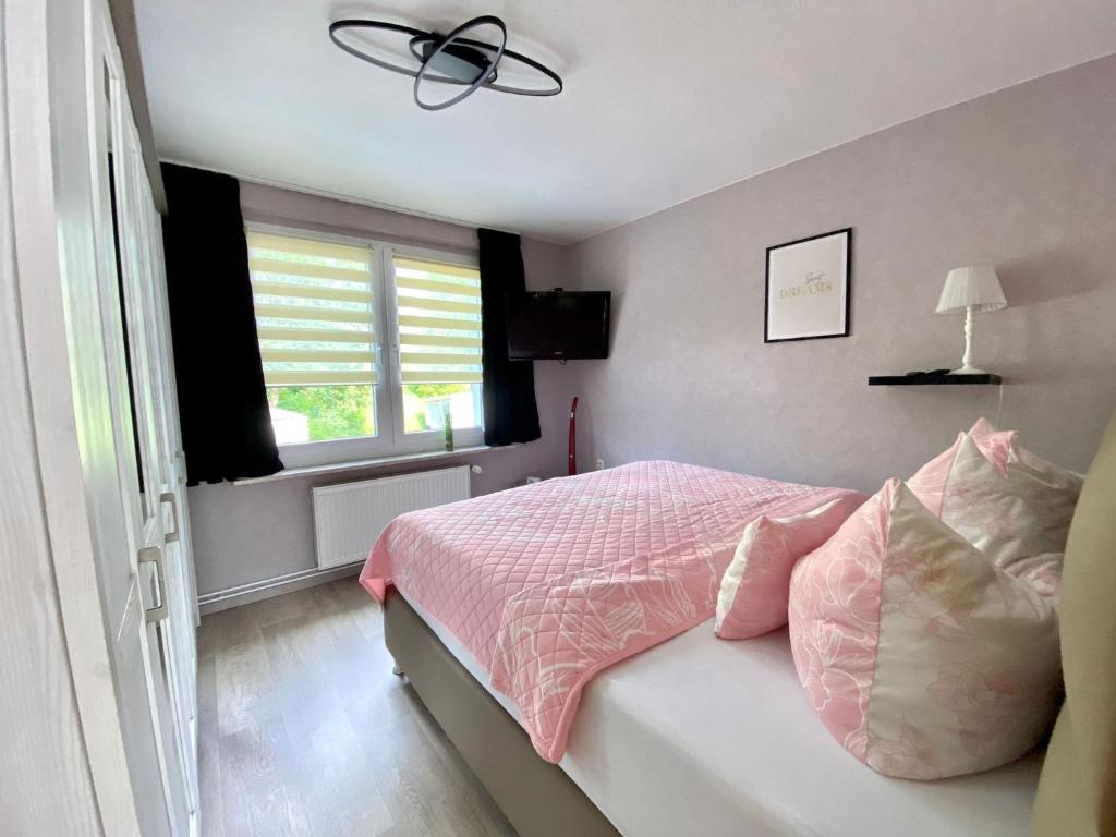 a bedroom with a bed with pink sheets and a window at Ferienhaus am Schloßpark in Elbingerode