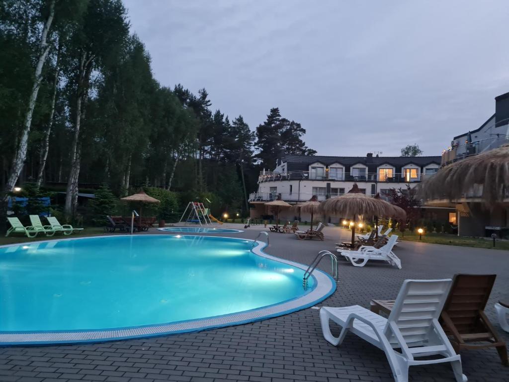 a large swimming pool with chairs and a resort at Baltic Sunset in Pobierowo