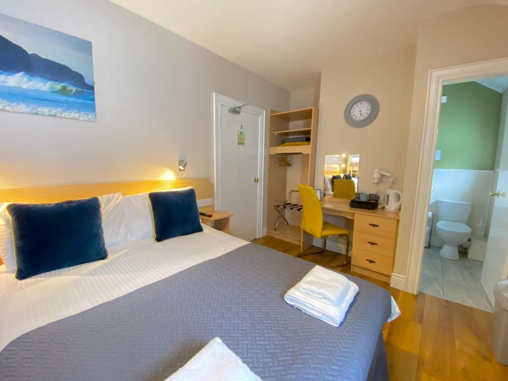 a bedroom with a large bed with a desk and a desk at Beulah Guest House in Portrush