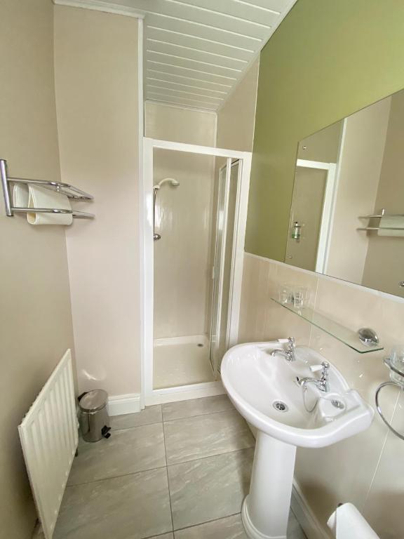 a white bathroom with a sink and a shower at Beulah Guest House in Portrush