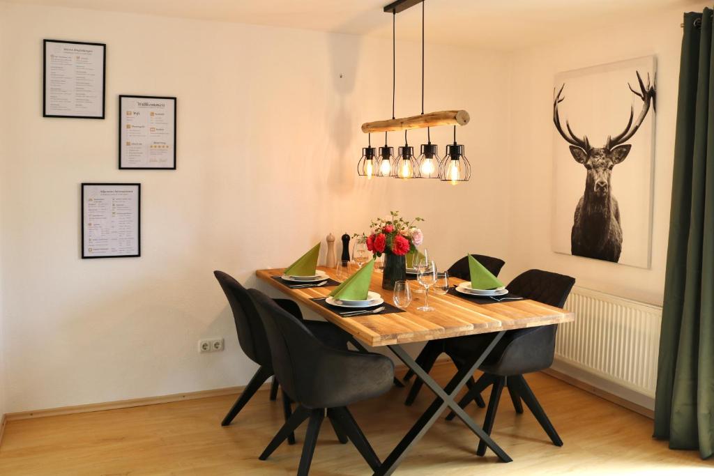 a dining room table with chairs and a deer head on the wall at Moderne Ferienwohnung im Allgäu in Erkheim