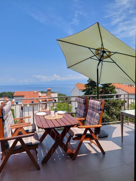 a table and chairs with an umbrella on a balcony at Falcon in Mali Lošinj