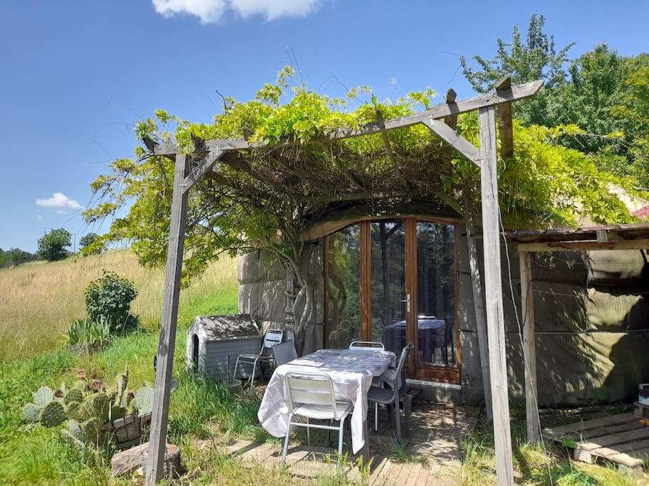 a pergola with a table and chairs in front of a cabin at Charmante Yourte contemporaine in Carmaux