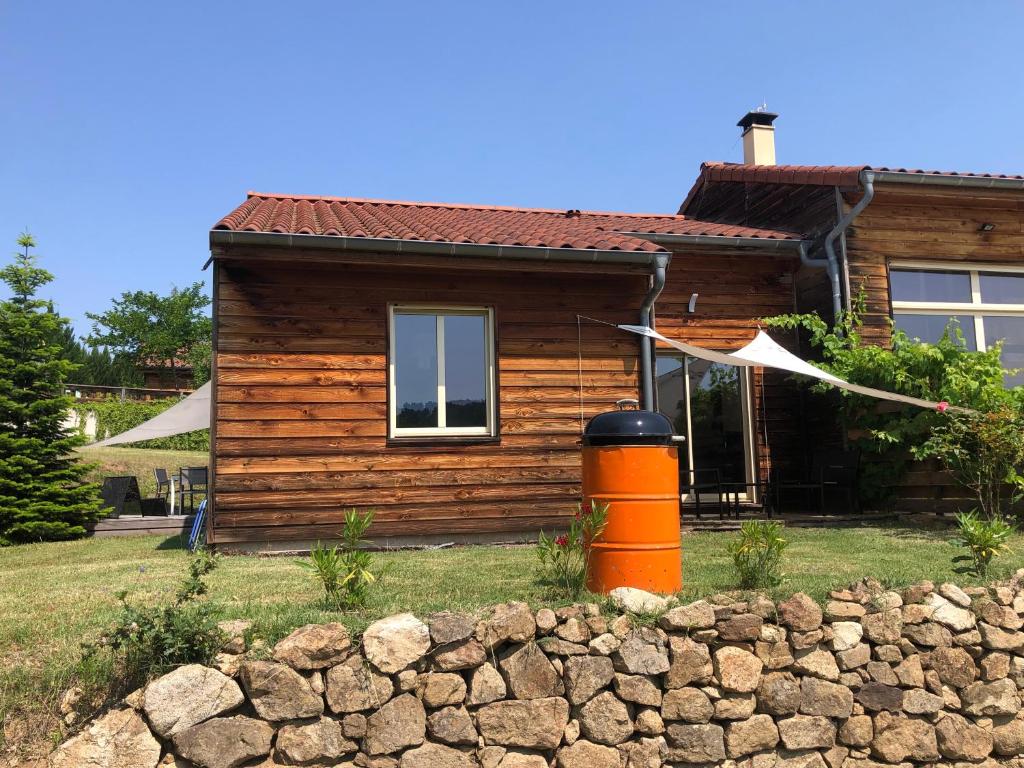 Cabaña de madera con pared de piedra frente a una casa en Le Montagnon, en Lupé