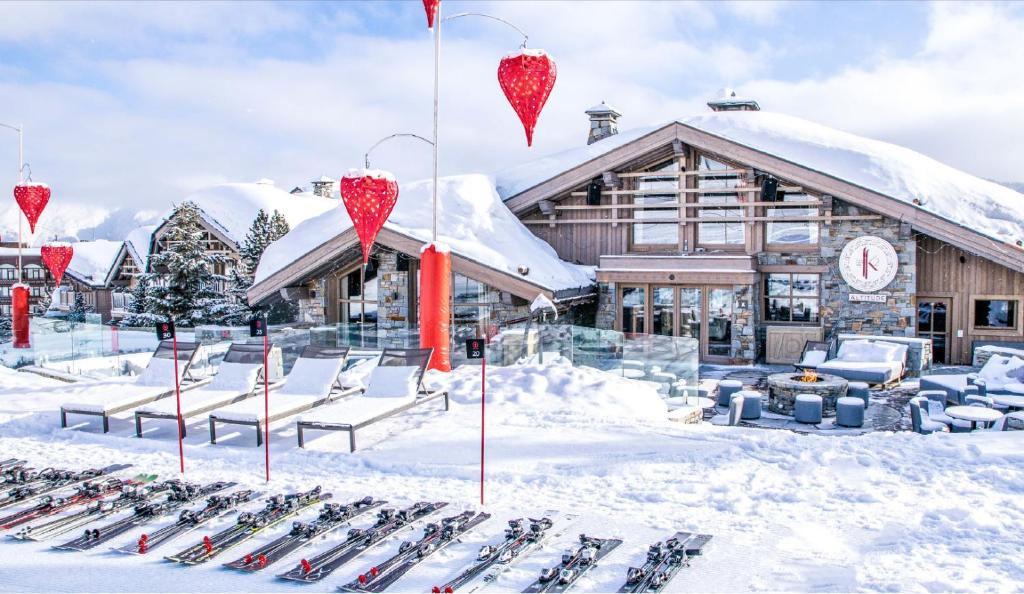 un grupo de esquís en la nieve frente a un lodge en Hotel Le K2 Altitude en Courchevel
