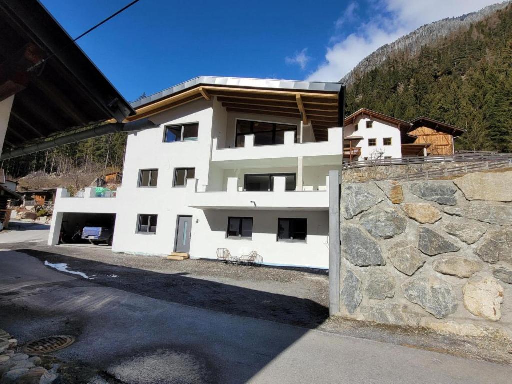 a white building with a stone wall in front of it at New apartment in the beautiful Pitztal in Oberlehn