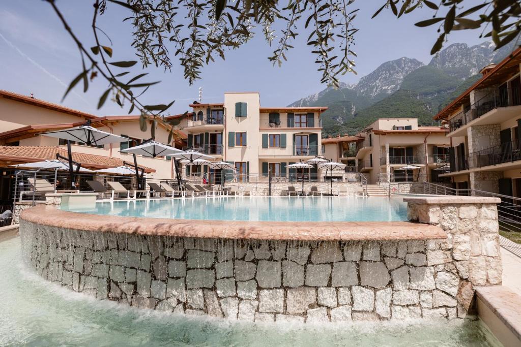 a swimming pool in a resort with mountains in the background at June Stay Lake Garda in Brenzone sul Garda